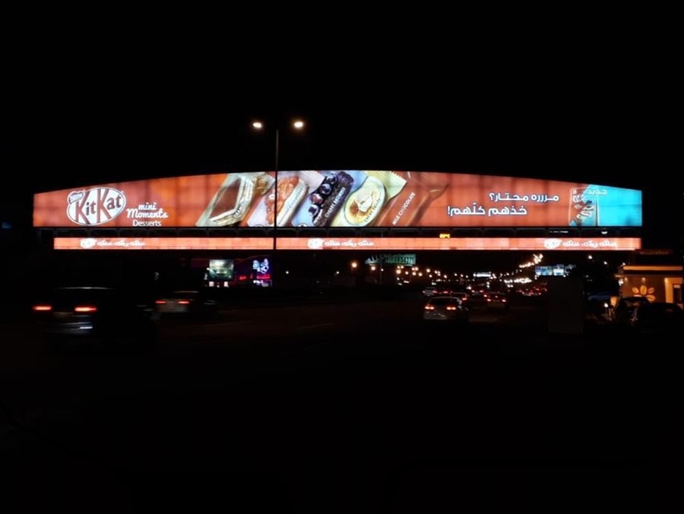 Illuminated advertising screens spanning a road at night